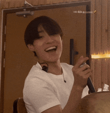 a man in a white shirt is smiling and holding a microphone in front of a door that says hbo on it