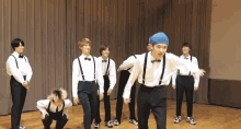 a group of young men in suspenders and bow ties are dancing on a stage
