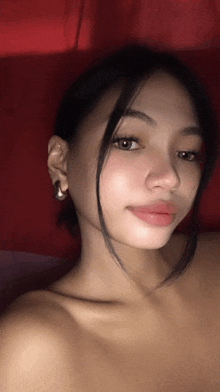 a young woman without a shirt is taking a selfie with a red background