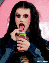 a drag queen is drinking from a can with a straw in her mouth