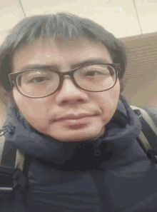 a man wearing glasses and a blue jacket