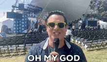 a man wearing sunglasses is holding a microphone and saying oh my god .
