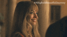 a woman is smiling in front of a sign that says #abigbold beautiful journey