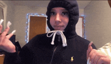 a girl wearing a black hoodie with a yellow polo logo
