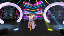 a woman in a purple robe is dancing on a stage surrounded by lights .