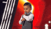 a young boy is holding a microphone in front of a red background .