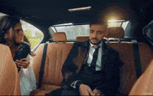 a man in a suit and tie is sitting in the back seat of a car