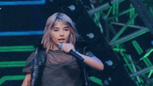 a woman in a wig is holding a microphone in her hand .
