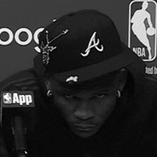 a black and white photo of a man wearing a atlanta hat