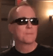a man wearing sunglasses and a black shirt is looking at the camera