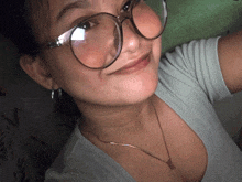 a woman wearing glasses and a butterfly necklace smiles for the camera