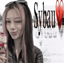 a woman holding a stuffed animal in front of a sign that says sybau