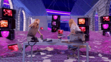 a woman sitting at a desk in a room with a lot of televisions