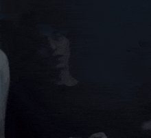 a person covering their mouth with their hand in the dark .