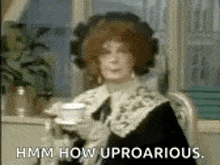 a woman is holding a cup of tea and saying `` hmm how uproarious . ''