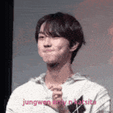a young man in a white sweater is making a funny face while holding his hands together .