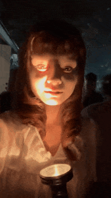 a girl with red eyes is holding a candle in her hand