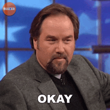 a man with a beard says okay on a blue background