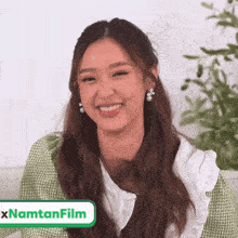 a woman is smiling in front of a sign that says ' xnamtanfilm '