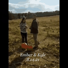a man and a woman are standing in a field of pumpkins .