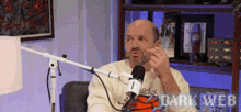 a bald man is sitting in front of a microphone with the words dark web on the bottom right