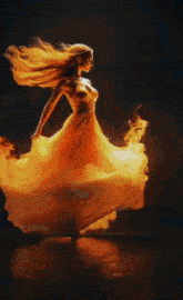 a woman in a fire dress is dancing on a stage with her arms in the air .
