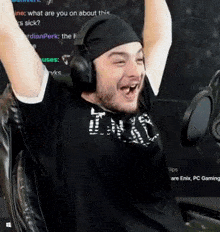 a man wearing headphones and a bandana is sitting in a chair with his arms in the air .