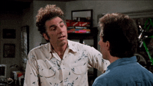 a man with curly hair is talking to another man in a room