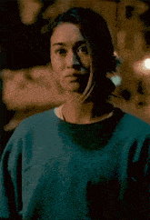 a woman wearing a blue sweatshirt is standing with her eyes closed .