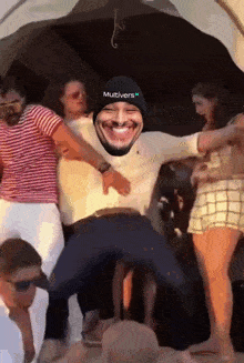 a man wearing a hat with the word multivers on it is dancing with a group of people
