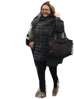 a woman is wearing a black coat and holding a black purse