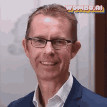 a man wearing glasses and a blue suit is smiling for the camera .