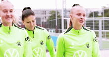 three female soccer players wearing green volkswagen shirts