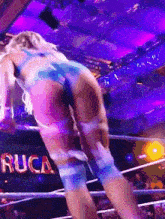 a woman is standing in a wrestling ring with a sign that says rucca on it .