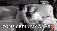 a man and a woman are kissing on a bed with the words `` come get in my arms '' written above them .