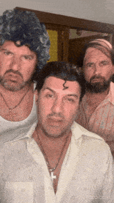 three men are posing for a picture and one has a cross on his chest