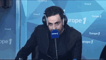 a man wearing headphones is talking into a microphone in front of a europe 1 sign