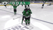 a group of hockey players holding up a green banner that says goal