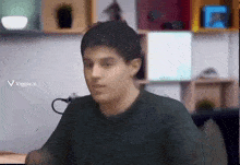 a young man is sitting at a desk in front of a computer screen .