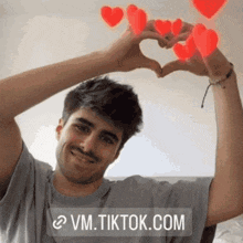 a man making a heart shape with his hands with hearts coming out of them