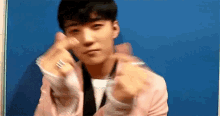 a man in a pink jacket is making a heart with his hands .