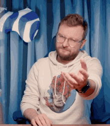 a man wearing glasses and a white sweatshirt with a picture of a woman on it