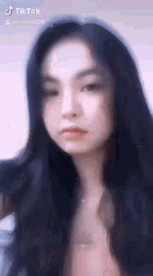 a close up of a woman 's face with long black hair looking at the camera .