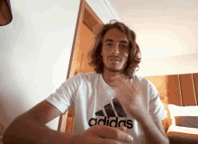 a man with long hair is wearing a white adidas t-shirt