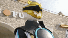 a robot is standing in front of a building with the letter fu on it