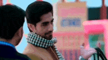 a man wearing a scarf is standing next to another man in front of a ferris wheel .