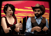 a man in a cowboy hat and a woman in a red dress holding a bottle