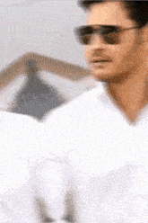 a man wearing sunglasses and a white shirt is walking