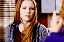a woman with long red hair wearing a grey sweater