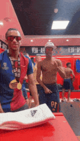 a man with a medal around his neck is standing in a locker room with other men .
